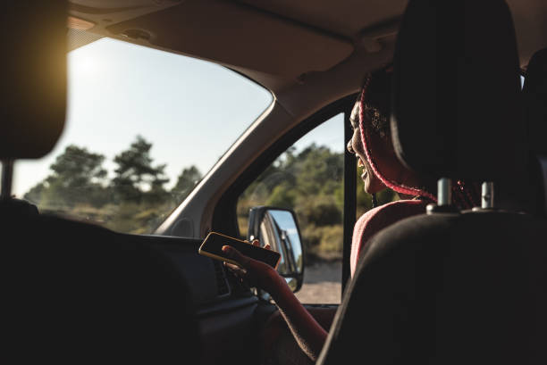 istock Young african girl having fun using mobile phone on the road inside mini van camper - Focus on face 1347122901