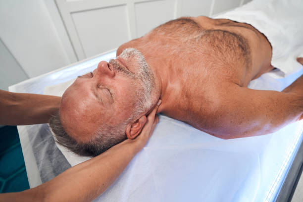 istock Masseuse hands massaging man neck at wellness center 1347123616