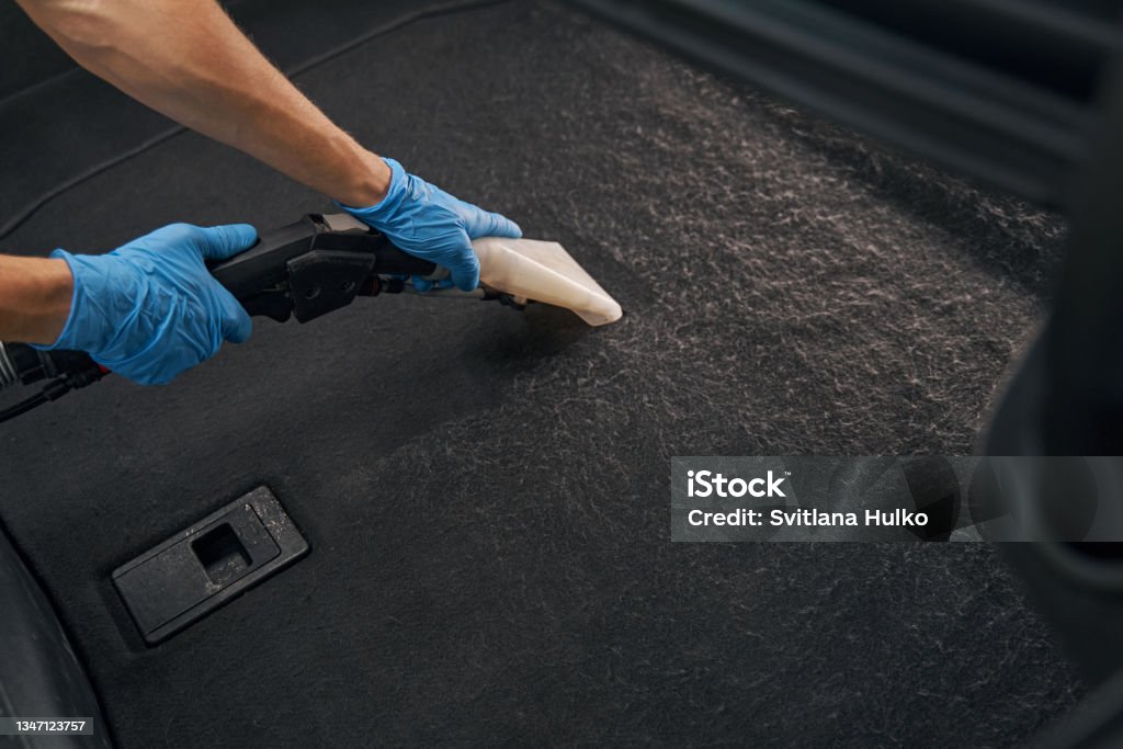 Professional worker using wet vacuum cleaner for dirty car interio Photo of cropped worker in protective gloves, using vacuum cleaner to wash car floor Car Stock Photo
