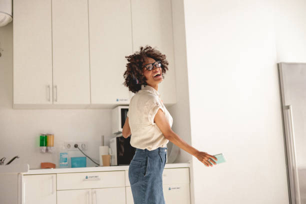 istock Happy Afro American woman holding mobile phone in hands while dancing 1347138385