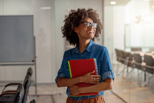 istock Pretty young woman in glasses standing with folder 1347138405