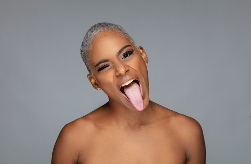 Portrait of afro young woman with short blonde hair sticking out her tongue trying to be ugly.