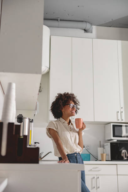 istock Smiling pretty lady enjoying hot drink in modern office kitchen 1347138461