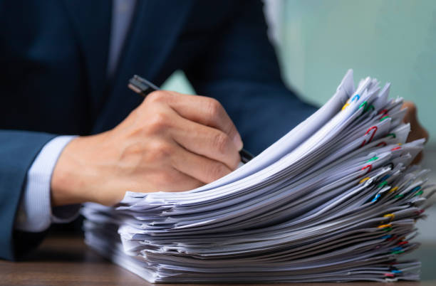 istock Stack paper with businessman signing document after reading the agreement in back, hand writing. 1347139475