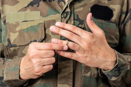 Hands of soldier male who is about to taking off his wedding ring.