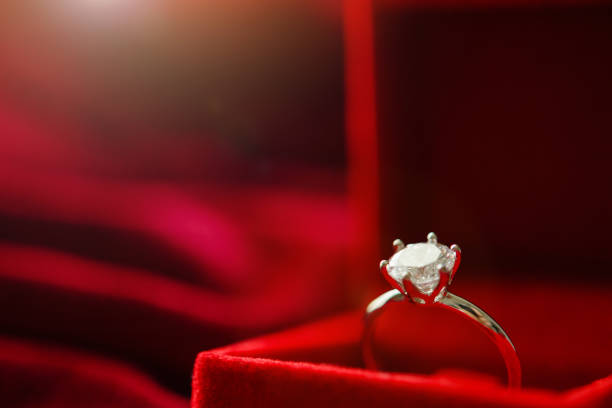 istock Diamond ring in jewelry gift box on red fabric background 1347145546