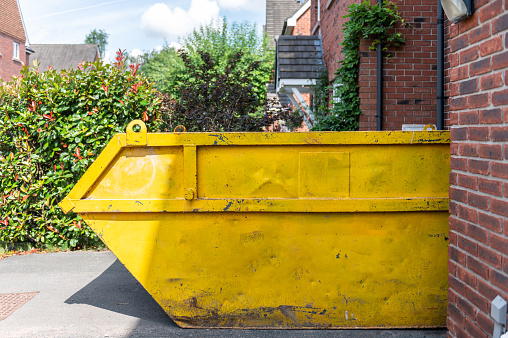 Big Yellow rubbish skip near the house. Rubbish removal hire during renovation of the house