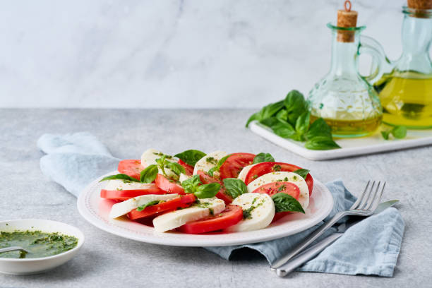 insalata caprese italiana con pesto. mozarella, pomodori, olio d'oliva, foglie di basilico - mozarella sul tavolo foto e immagini stock