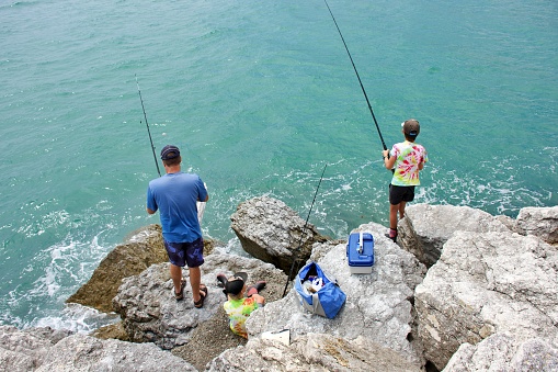 A Father and his Child on a Fishing Trip off Coastal Rocks in summer.