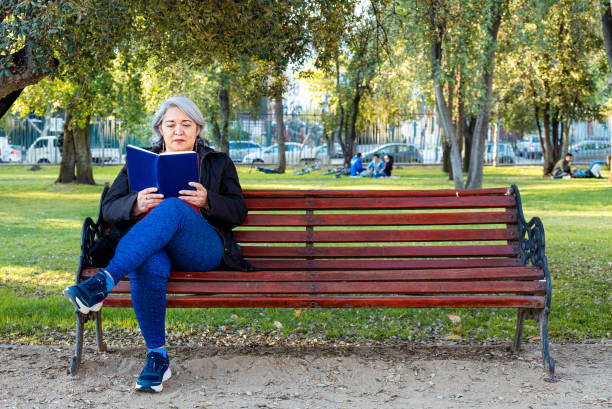 istock Mature woman reading a book at park 1347148067