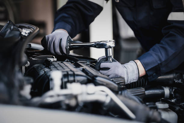 Professional mechanic working on the engine of the car in the garage. Professional mechanic working on the engine of the car in the garage. Car repair service. The concept of checking the readiness of the car before leaving. blue collar worker photos stock pictures, royalty-free photos & images