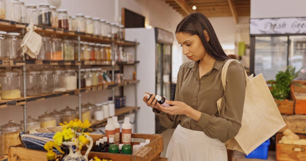 Shot of a young woman reading the label of a bottle in a grocery store stock photo