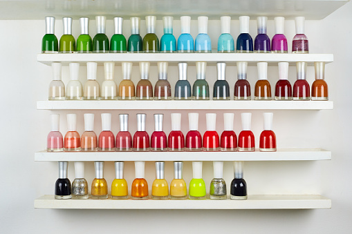 Set of different nail polishes on shelves on white background