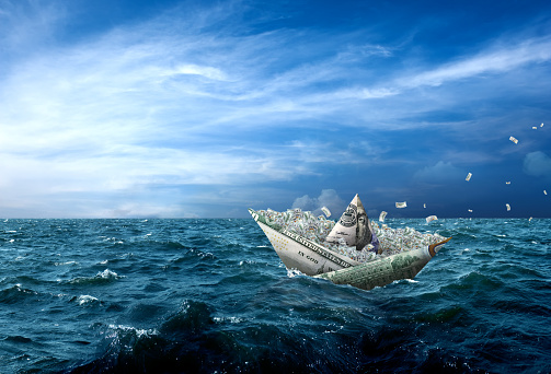 Conceptual money boat carrying large group of US dollars in stormy seascape