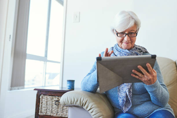 istock Shot of a senior woman using a digital tablet while relaxing at home 1347157993