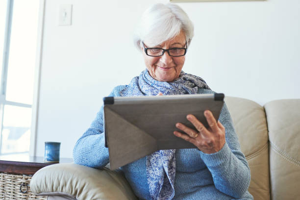 istock Shot of a senior woman using a digital tablet while relaxing at home 1347158011