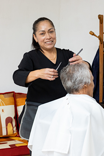 portrait of a female stylist cutting an older man's hair