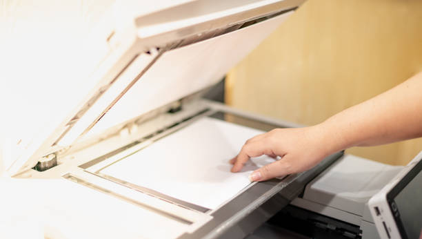 istock Business woman hand lay down or take papers from laser copy machine for process paperwork on laser print cartridge at the office. 1347160414