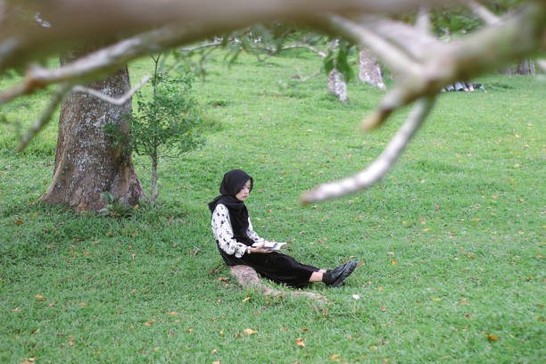 istock Young Hijab women sitting reading enjoying at park 1347160415