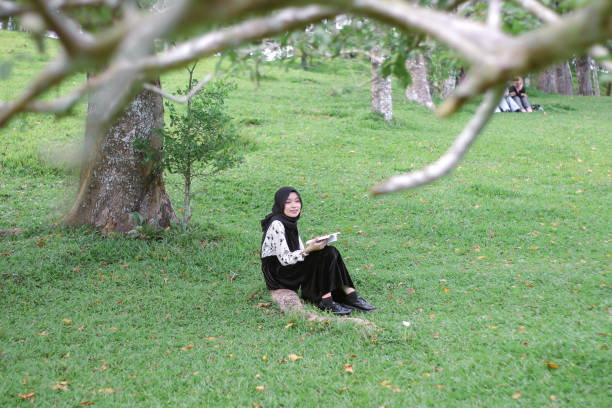 istock Young Hijab women sitting reading enjoying at park 1347160430