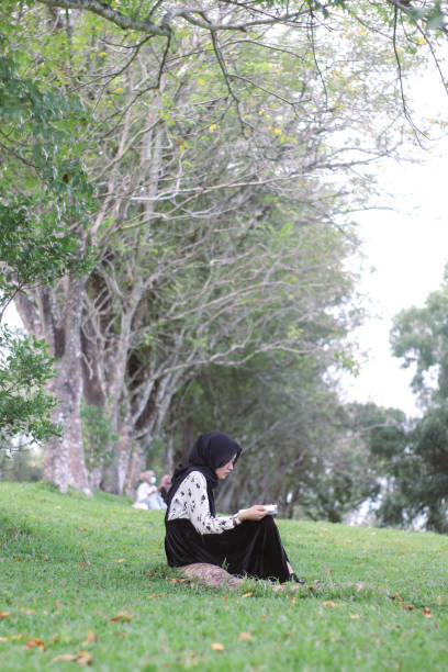 istock Young Hijab women sitting reading enjoying at park 1347160462