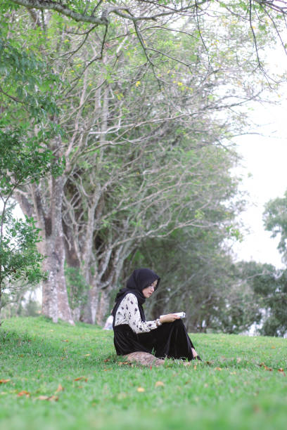 istock Young Hijab women sitting reading enjoying at park 1347160463