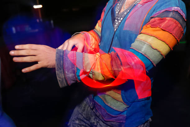 Close-up shot of unrecognizable Caucasian man dancing on a festival music, wearing a colorful clothing.