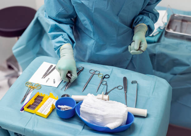 врач расставляет хирургическое оборудование на столе - one mid adult man only стоковые фото и изображения