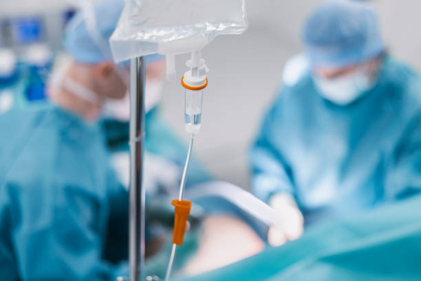 istock IV drip with surgeons in background at hospital 1347166116