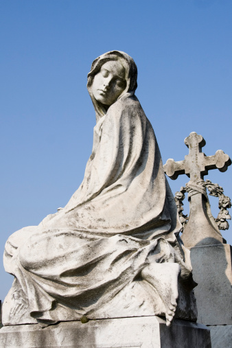 statue of a woman with a cross in a cemetery in milan
