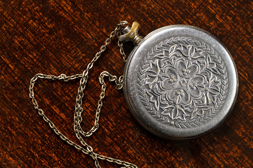 An old metal medallion with a chain and ornament on the surface. Medallion on the background of a tree.