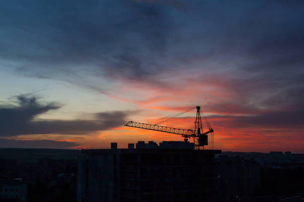 istock Tower crane and building construction site silhouette at sunrise. 1347177846