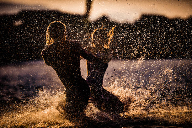 istock Playful couple having fun while spinning in the sea at sunset. 1347182142