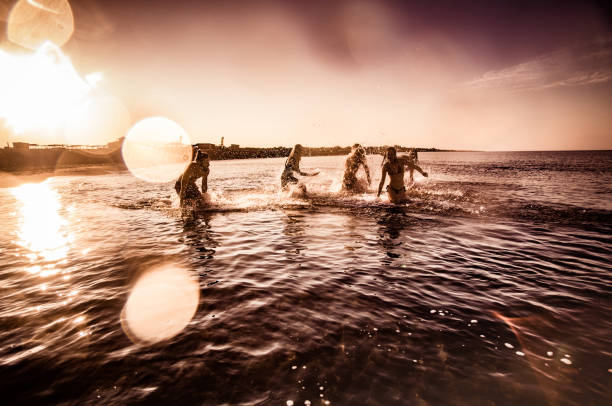 istock Group of happy people having fun while playing in the sea at sunset. 1347182843