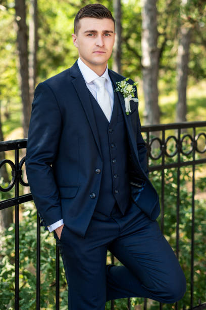 istock Handsome young groom wearing elegant dark blue suit looking at camera outdoors  portrait. Stylish groom fashion. 1347182967