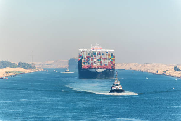 Large container vessel ship passing Suez Canal Ismailia, Egypt - November 5, 2017: Large container vessel ship MSC Maya passing Suez Canal in the sandy haze in Egypt. Tugboat accompanies the ships. red sea stock pictures, royalty-free photos & images