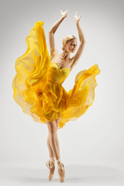 dancing woman in yellow dress. ballerina in shoes dance modern art ballet over light gray background. graceful girl stretching hands up - dancer jumping ballet dancer ballet imagens e fotografias de stock