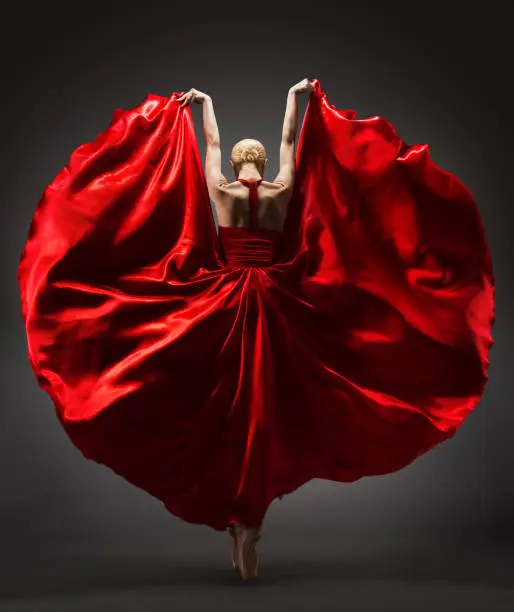 Ballerina Dancing in Red Flying Silk Dress Rear Back Side View. Graceful Woman Ballet Performer in Flamenco Skirt. Expressive Passion Dance in Motion over Black Background