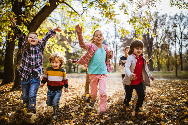 istock Playful kids screaming while running with their arms raised in autumn day. 1347185224