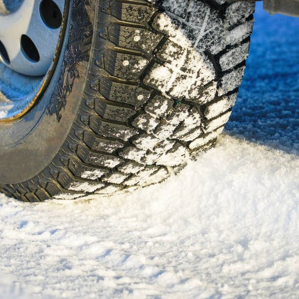 istock Studded winter car tires on snow-covered road 1347187608