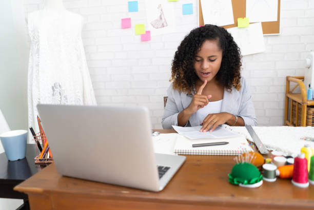 istock Young beautiful Afro-American designer clothes notes ideas in  document in her office 1347189459