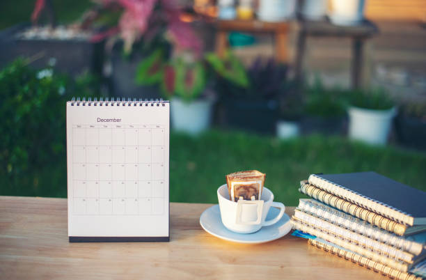 istock 2022 Calendar and Diary book on School table for Student, study for exam. Wooden desk with calender, notebook, and cup of coffee in garden. Desk for student work at home concept. 1347190848