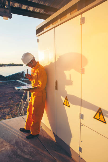 male electricity engineer inspect and maintenance electric power system in generator at solar plant. technician checklist work and service on switchgear at substation control. - safety sign protective workwear factory imagens e fotografias de stock