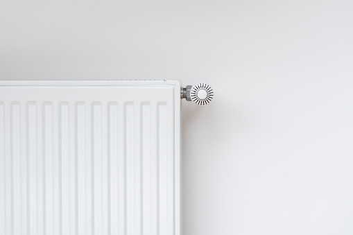 New modern radiator against white copy space wall. Central heating system in contemporary house. Saving energy, consumption of natural resource and warm home concept