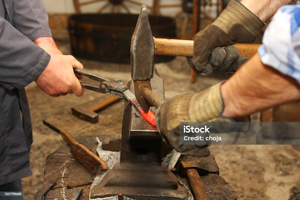 Herrero es hammering una pieza de hierro rojo vivo - Foto de stock de Acero libre de derechos