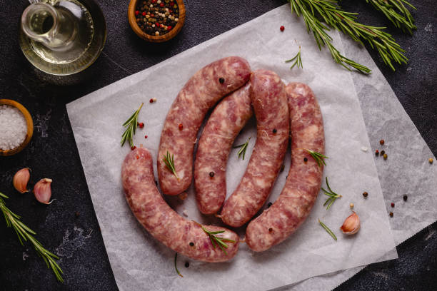 istock Raw sausages and ingredients for cooking on a black stone table 1347203708