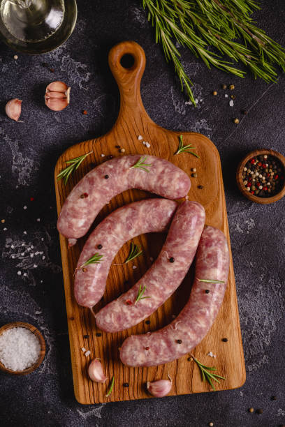 istock Raw sausages and ingredients for cooking on a black stone table 1347203709
