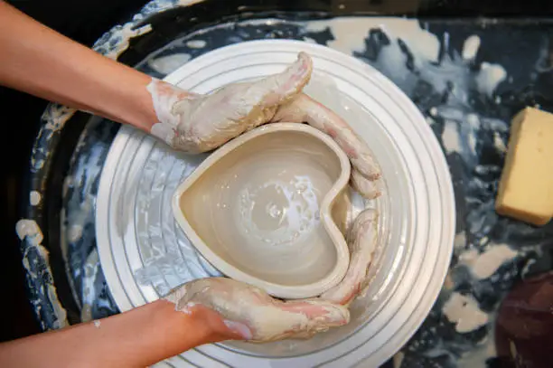 Woman white hands doing pottery top view pottery wheel horizontal no face close up