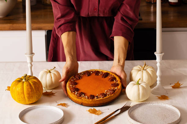 istock Traditional pumpkin pie on table with woman hands 1347204041