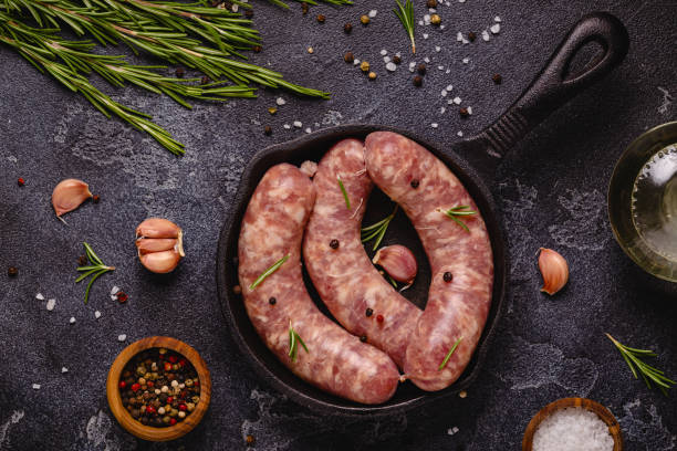 istock Raw sausages and ingredients for cooking on a black stone table 1347204111